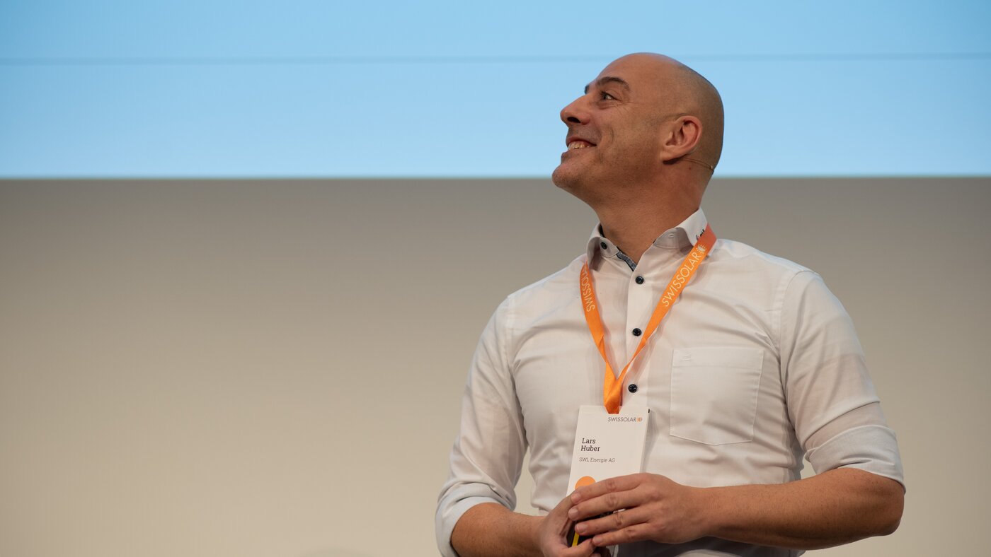 Mann mit weissen Hemd und orangenen Lenyard  | © Swissolar / Céline Farias