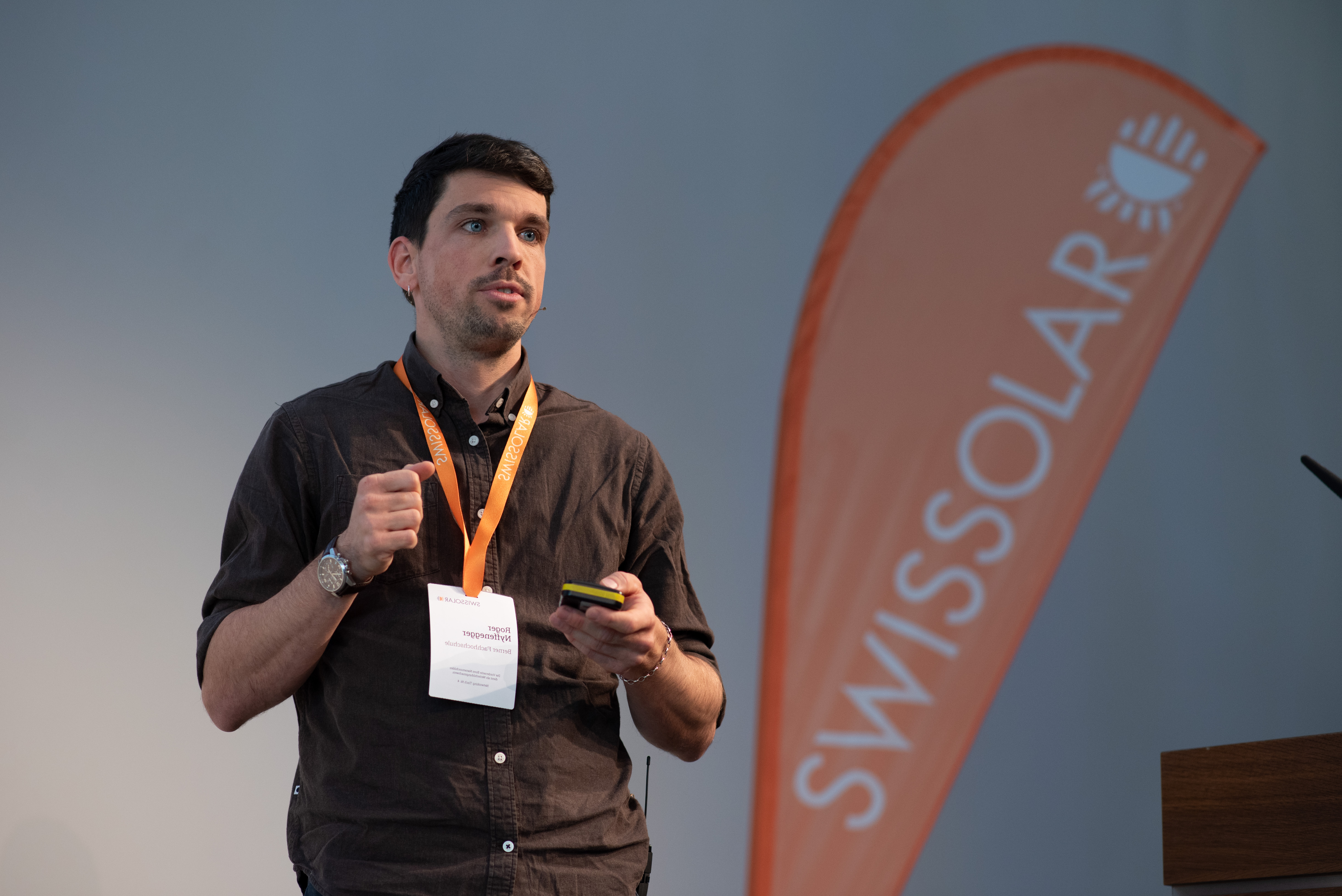 Mann mit orangener Flagge im Hintergrund | © Swissolar / Céline Farias